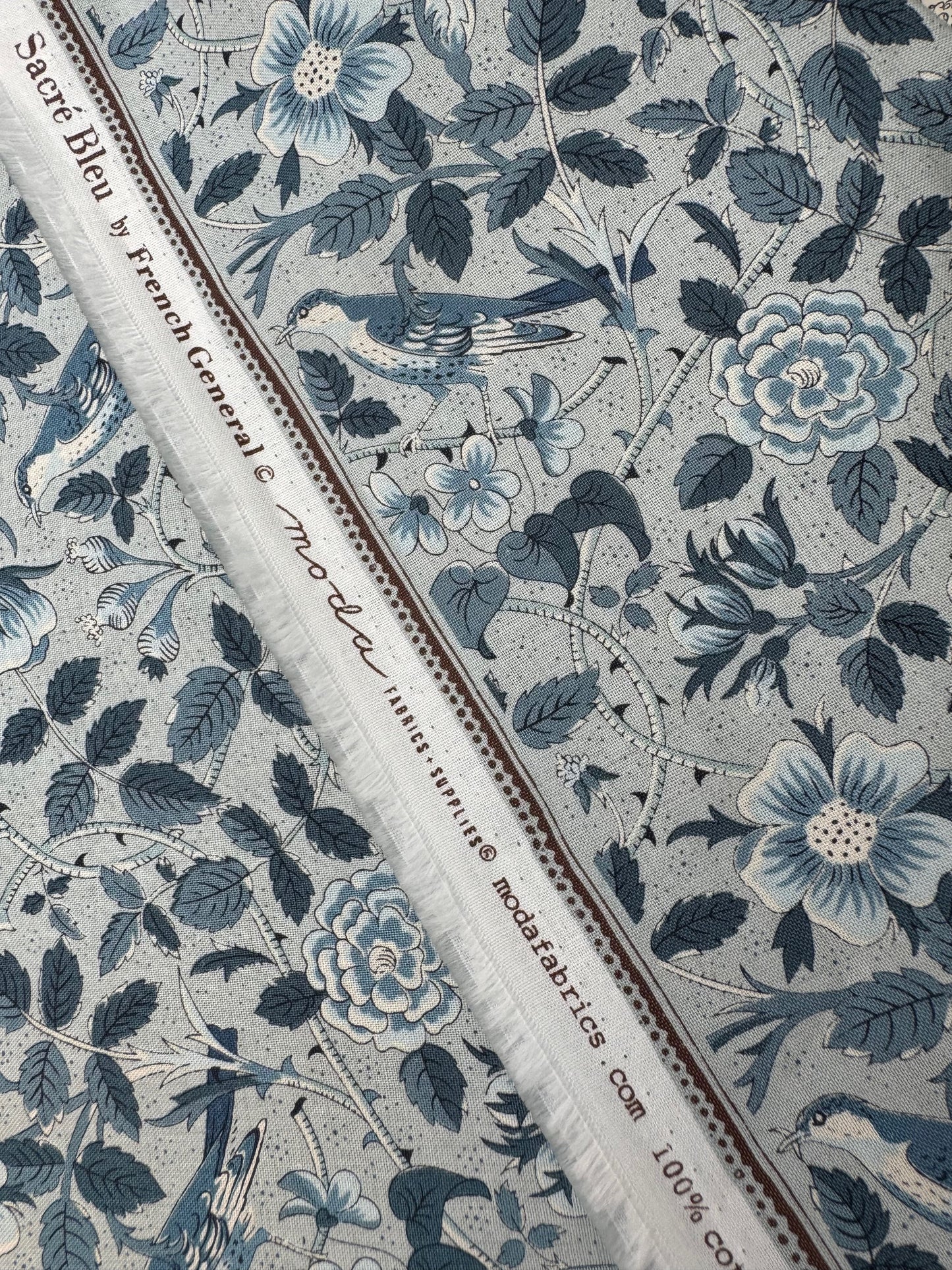 Floral and leaf patterned fabric with visible brand name.