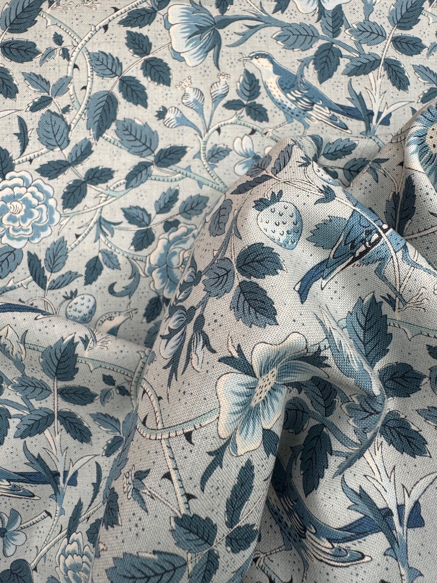 Close-up of a fabric with blue floral and leaf pattern on a light blue background