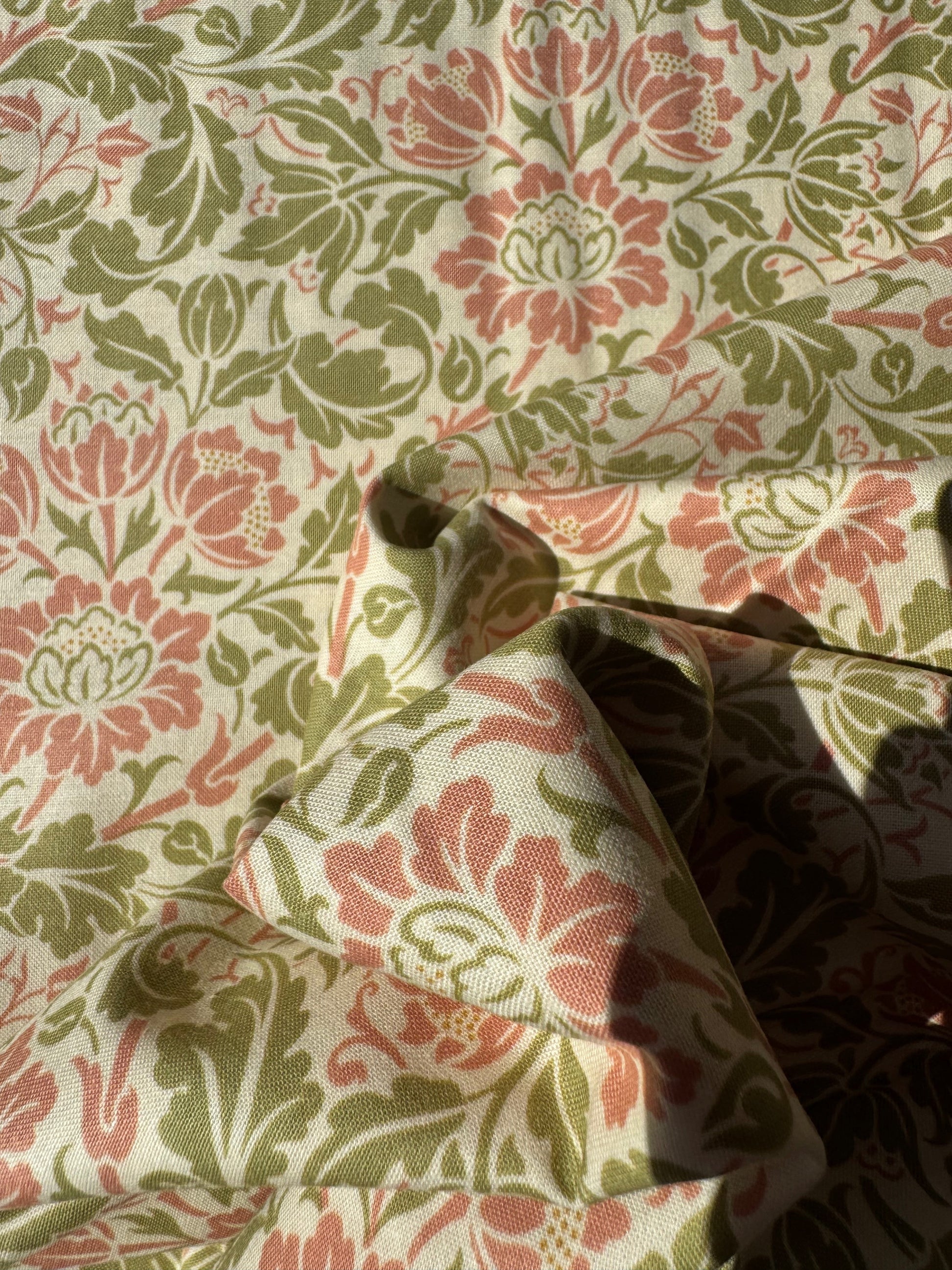 Close-up of floral patterned fabric with pink and green colors.