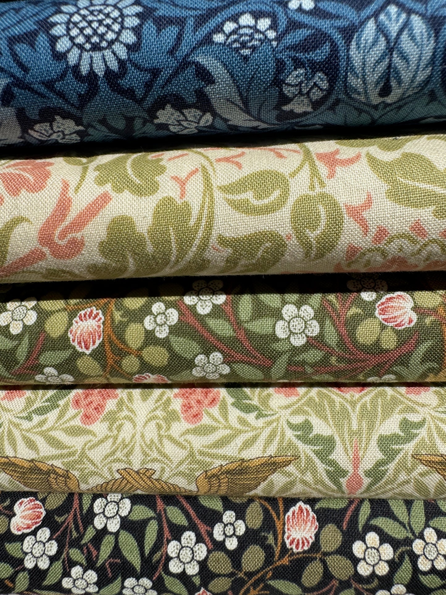 Stack of fabric swatches from Barbara Brackman Morris Muse collection with floral patterns in various colors