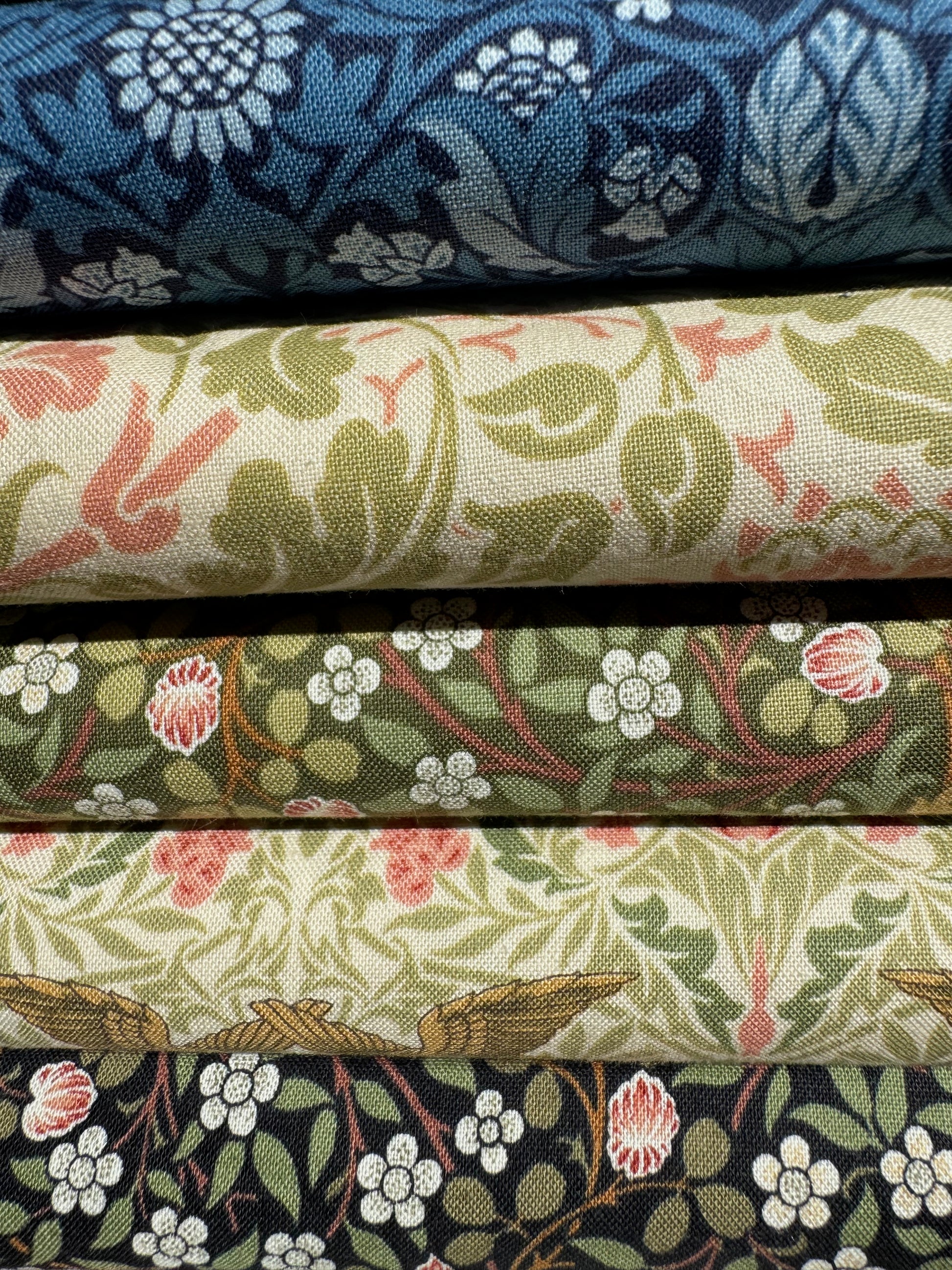 Stack of fabric swatches from Barbara Brackman Morris Muse collection with floral patterns in various colors